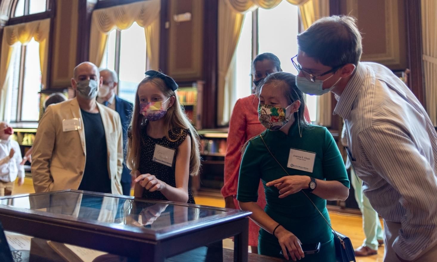 a couple and a family look closely at a museum case
