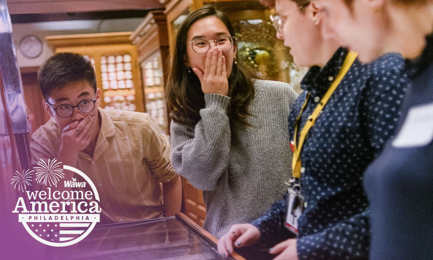Four people standing over a drawer with a "Wawa Welcome America" logo in the bottom corner