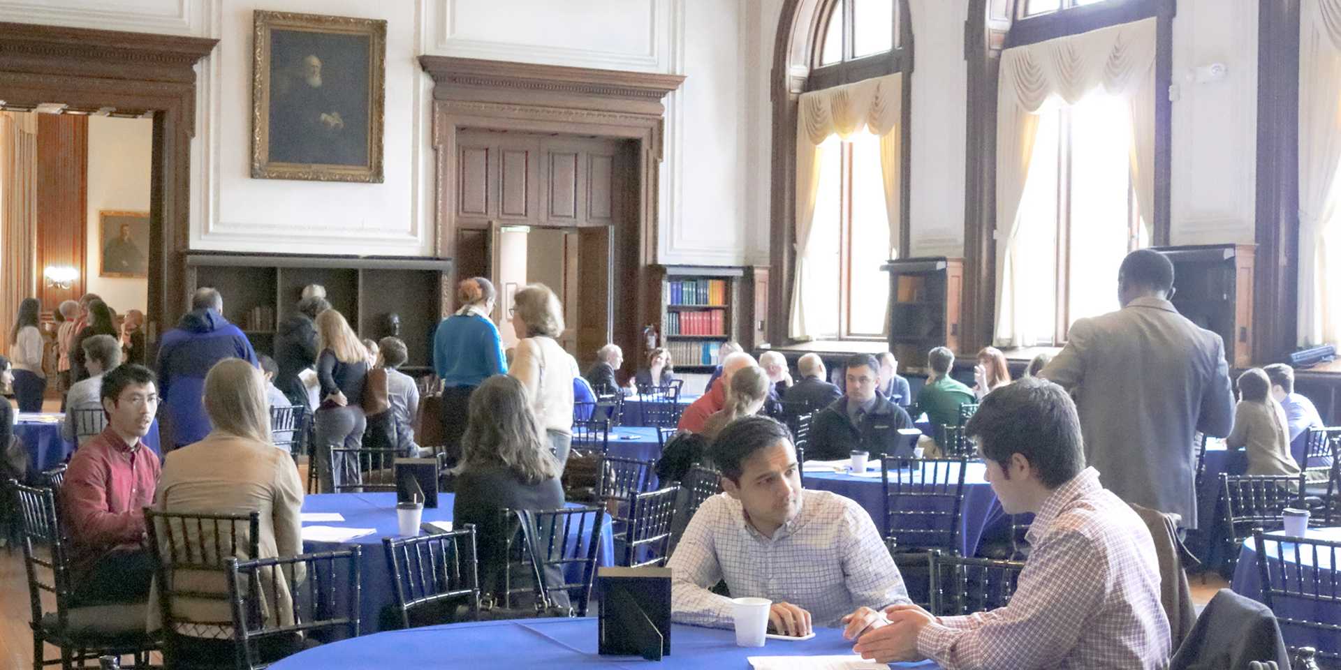 Groups of people scattered across several tables in a large room