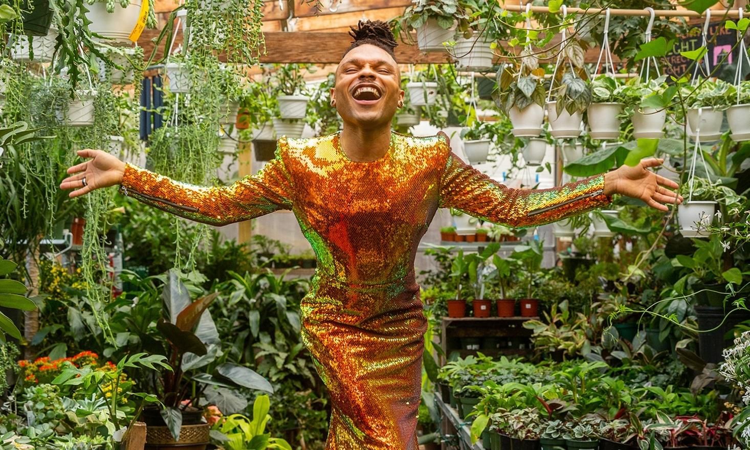 Photo of the Plant Kween in gold dress surrounded by green plants